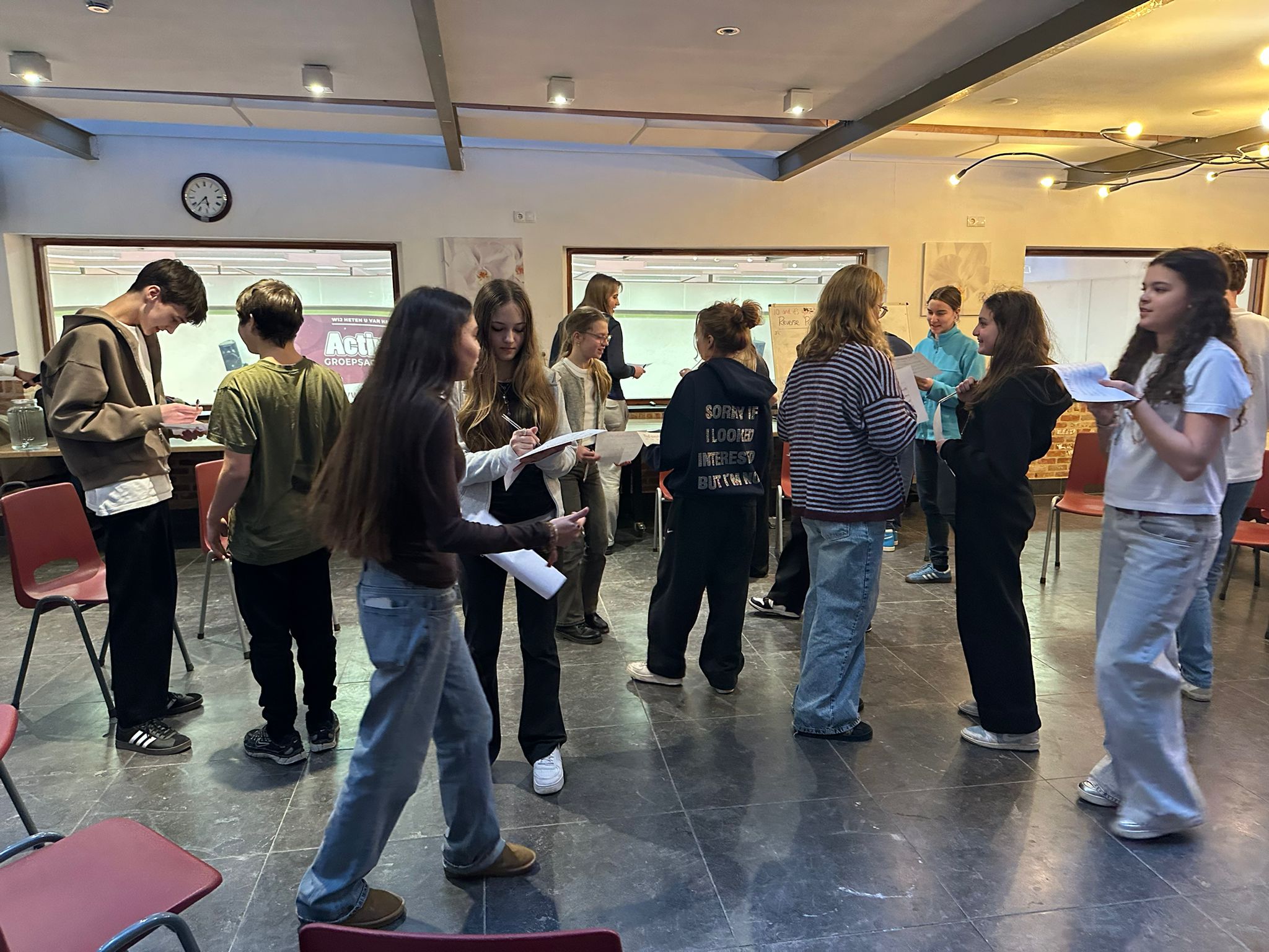 Students walking around with bingo worksheets, approaching each other