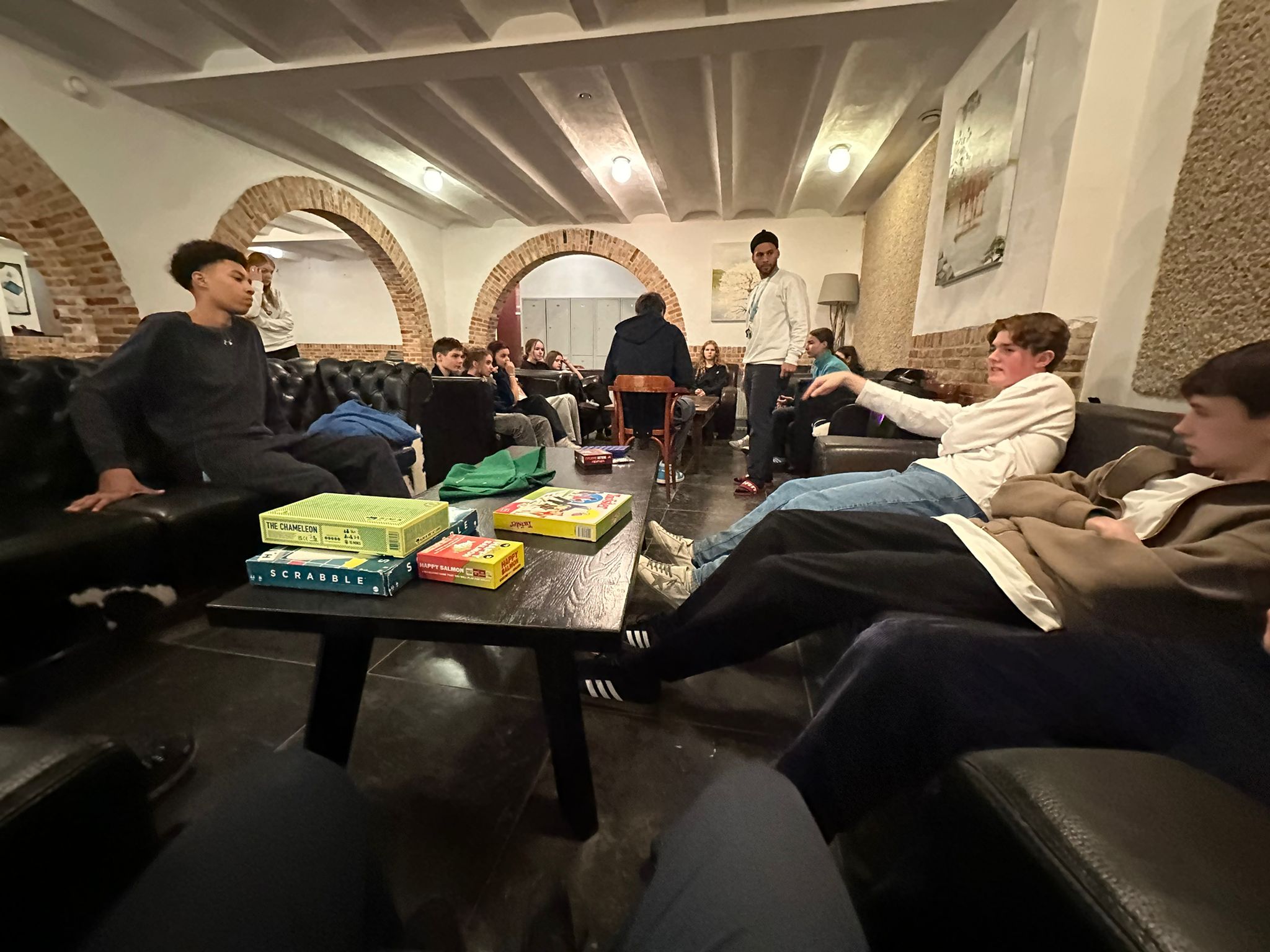 The lounge area — leather sofas, board games, warm lighting