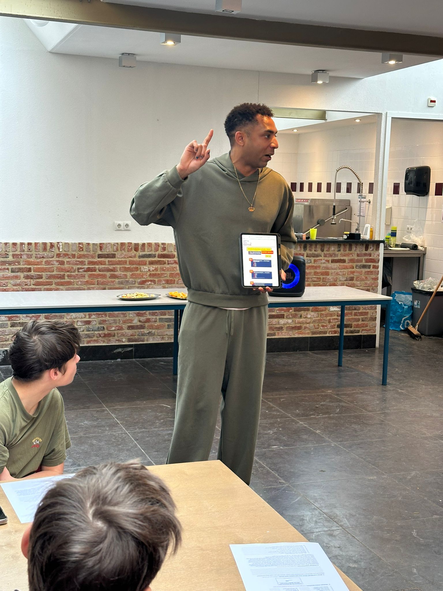 English level assessment in progress — student writing on worksheet with iPad nearby