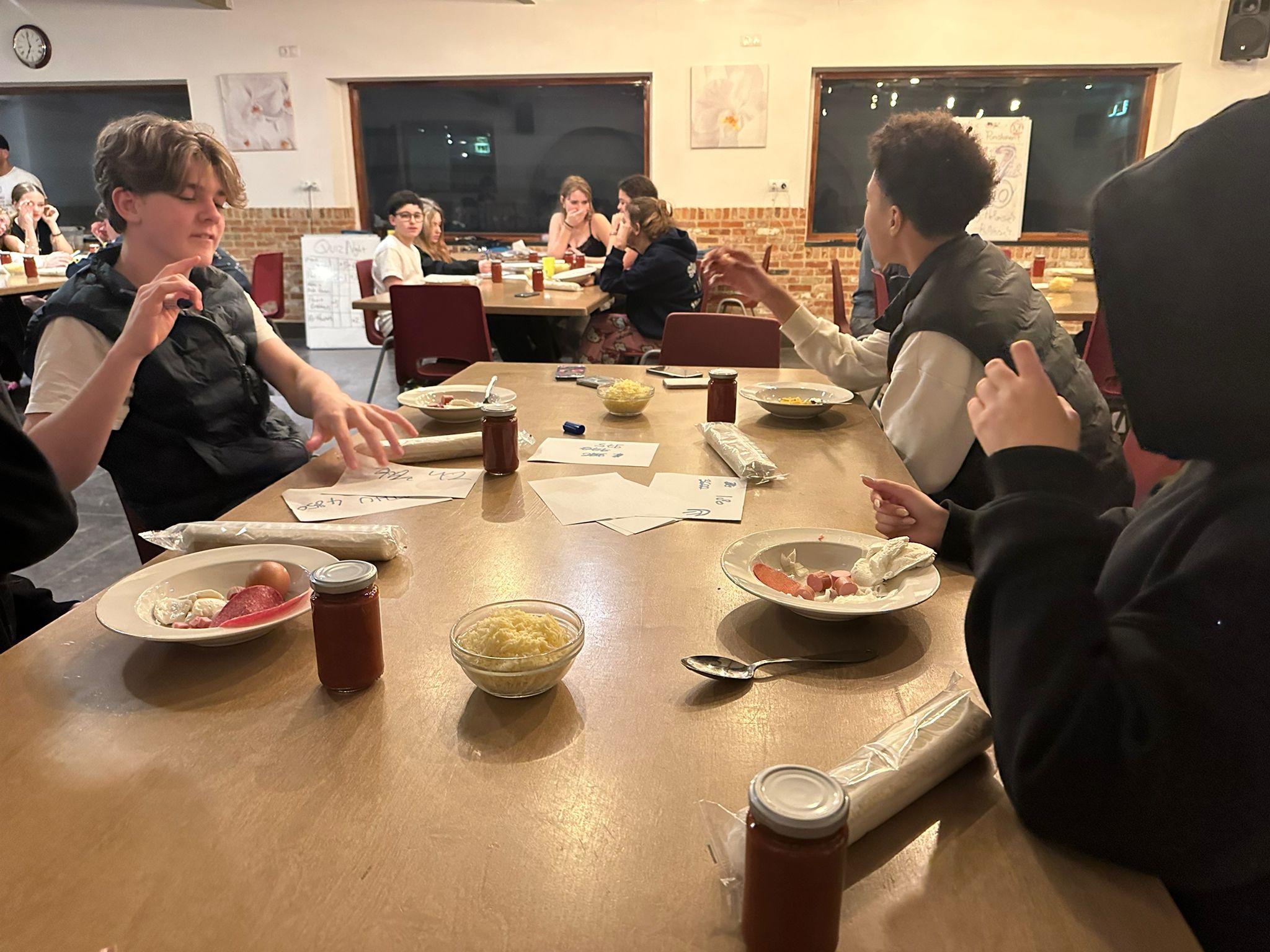 Table quiz before pizza cooking — questions projected on screen