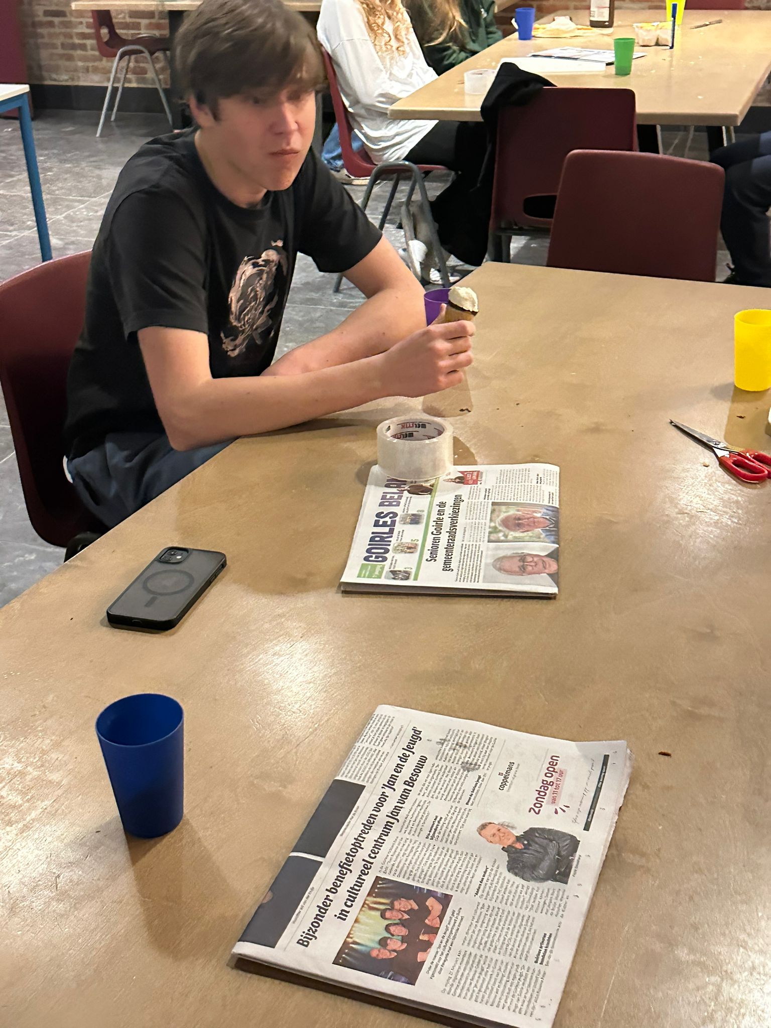 Student sitting at a table reading a newspaper during downtime