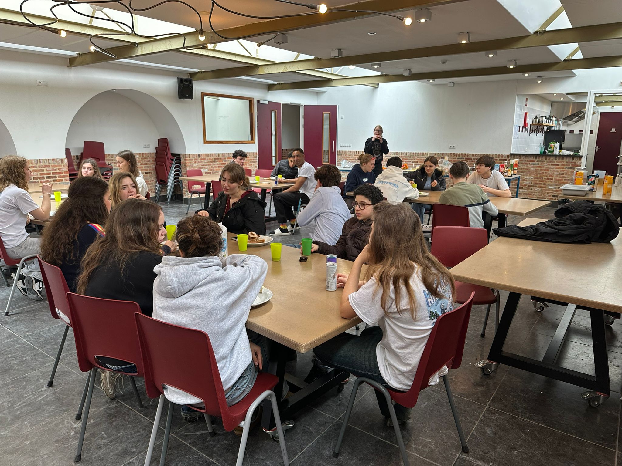 Students and facilitators eating together in the cafeteria — tables of mixed ages and nationalities